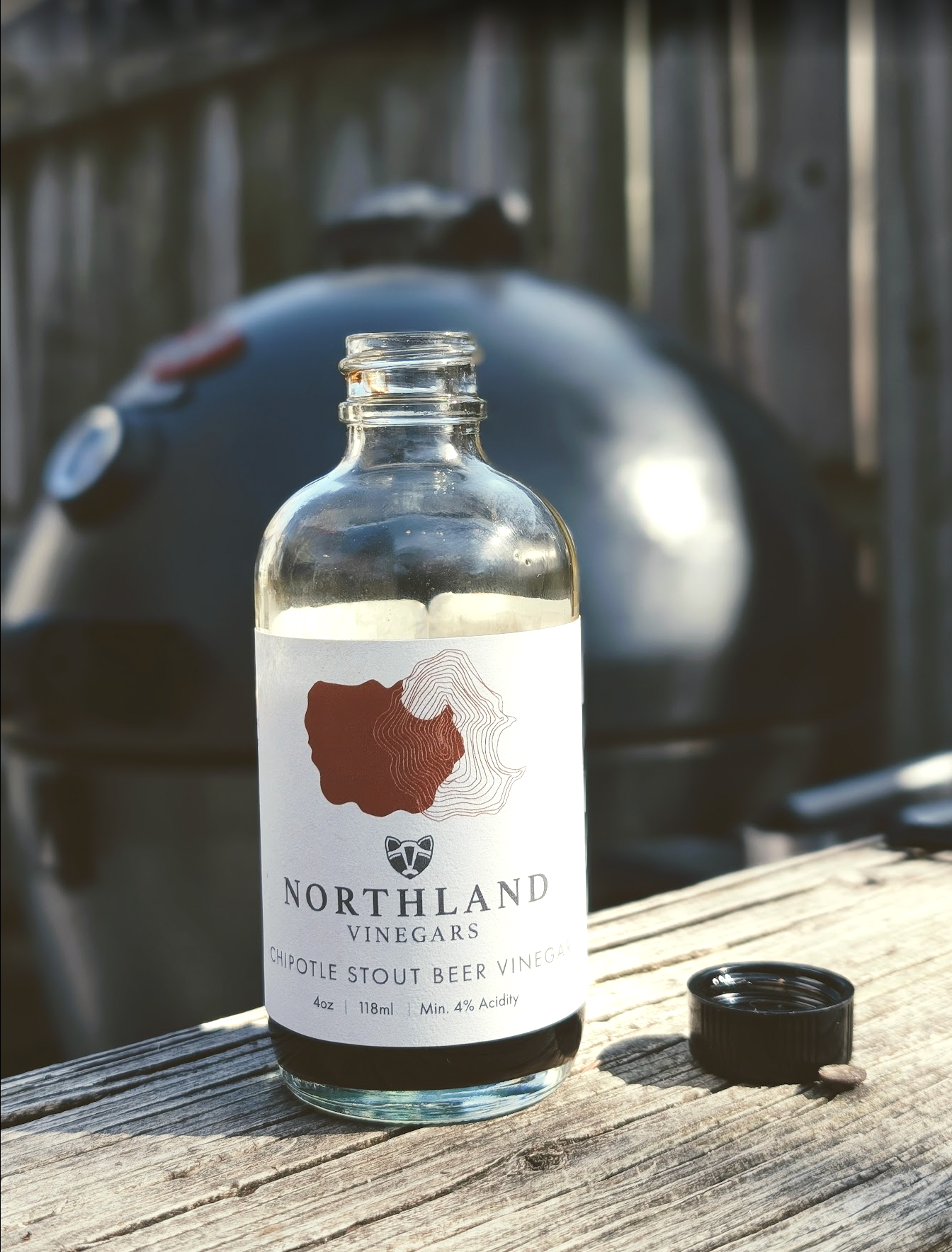 Bottle of Northland Vinegars on a wooden surface with a background of a grill.