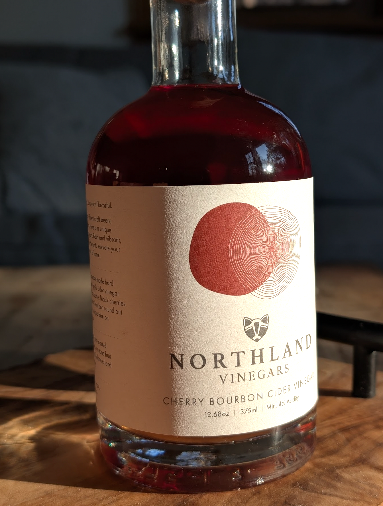 Bottle of Northland Vinegars Cherry Bourbon Cider Vinegar on a wooden surface with a blurred background